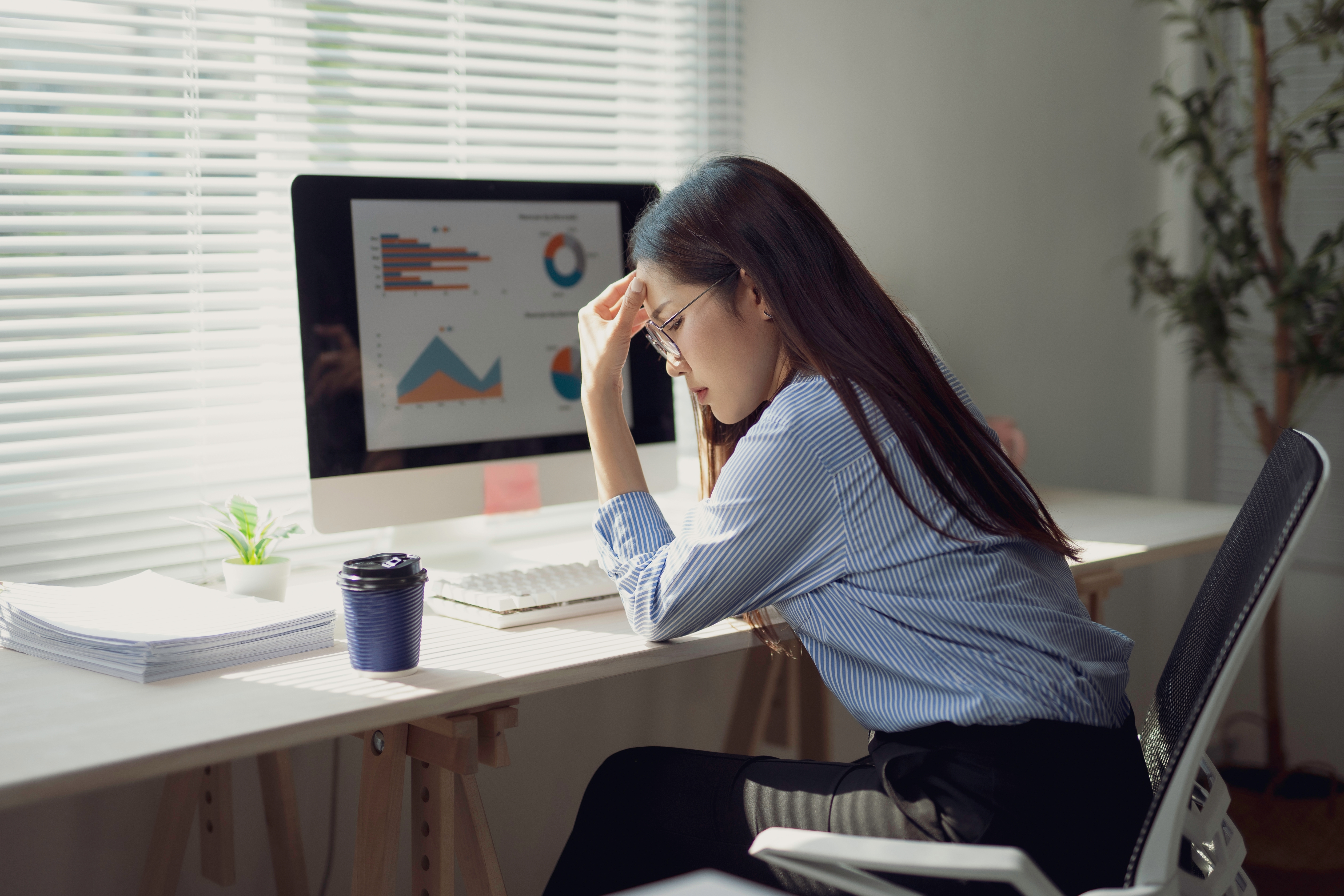 Small business owner sitting at her desk looking frustrated while reviewing marketing metrics on her computer screen.